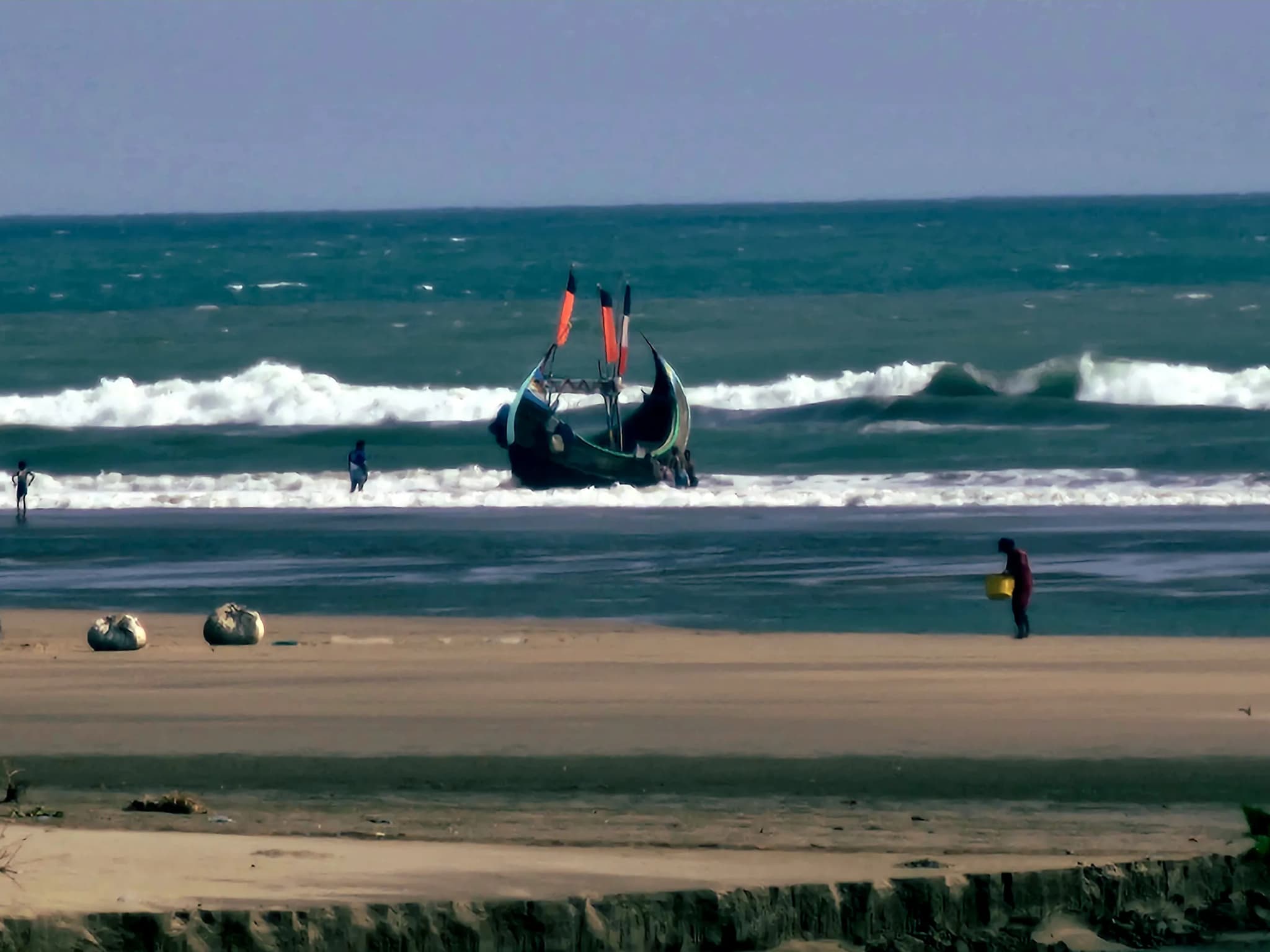 Wooden moon boat entering the breaking sea waves at low tide